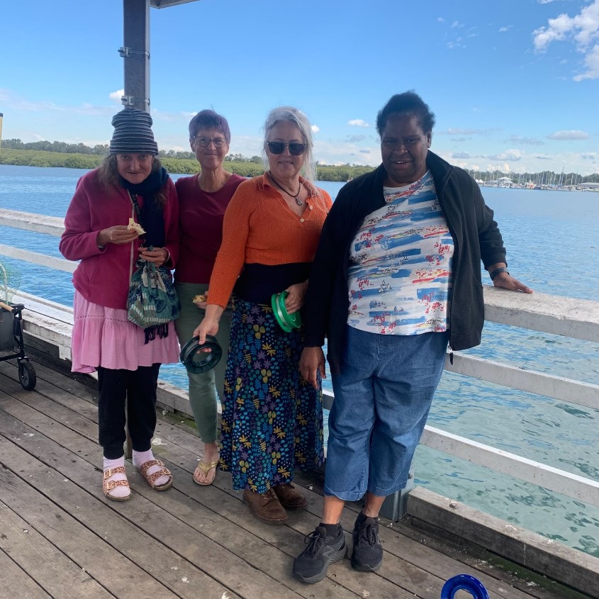 Participants of Taums Fishing day leaning against a railing at the beach